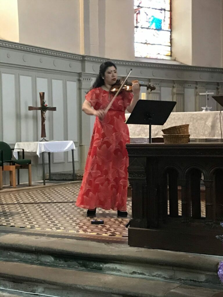 Yumiko jouant de son violon devant les anciens dans l'église de Lachapelle-sous-Chaux